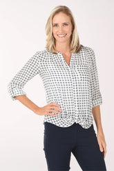 Woman wearing a navy and white checkered blouse with navy pants on a white background