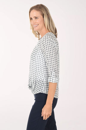 Woman wearing a navy and white checkered blouse with navy pants on a white background