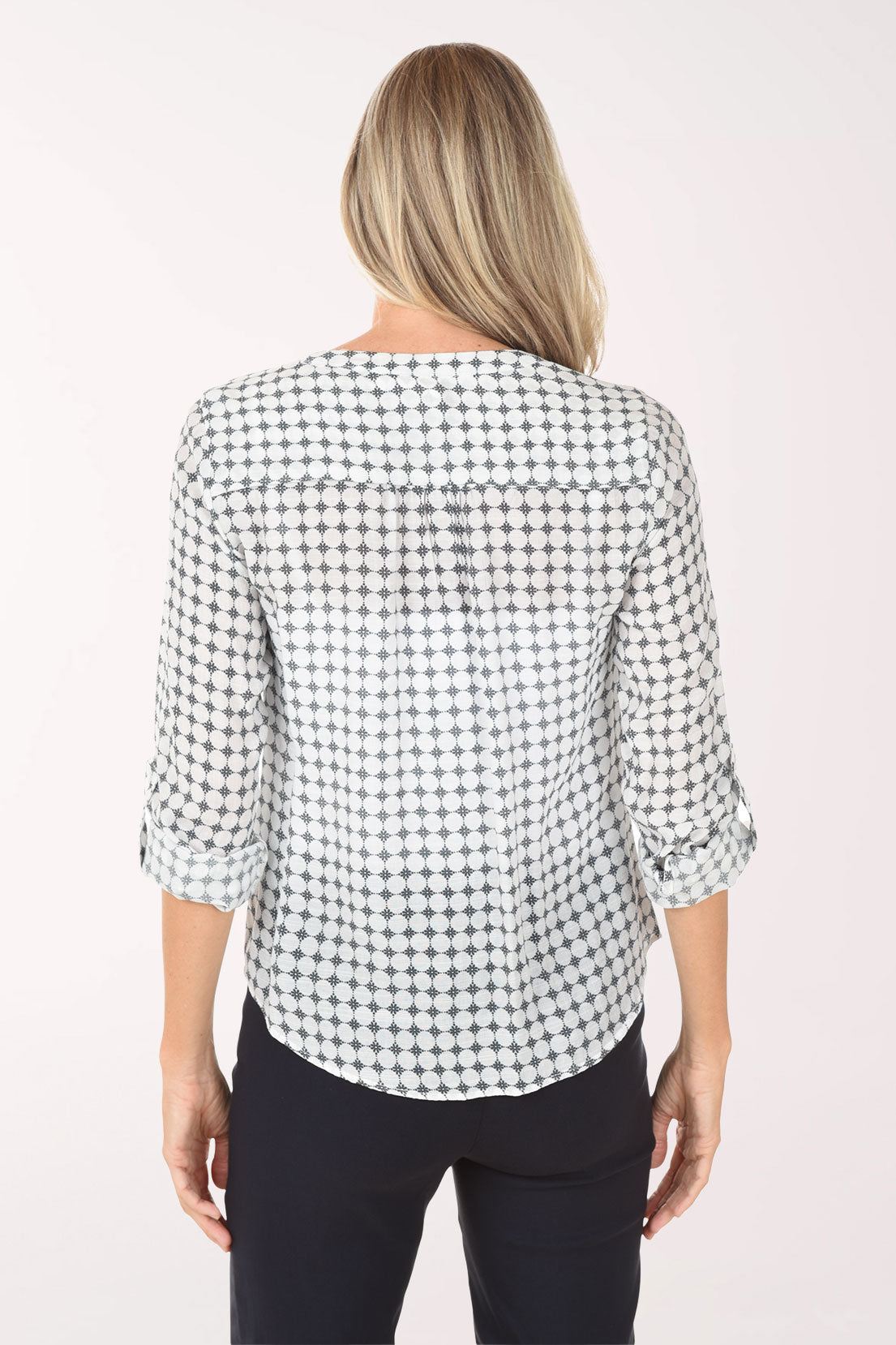 Woman wearing a navy and white checkered blouse with navy pants on a white background