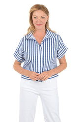 Woman wearing a blue and white striped shirt and white pants on a white background.