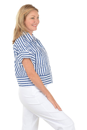 Woman wearing a blue and white striped shirt and white pants on a white background. Side shot.