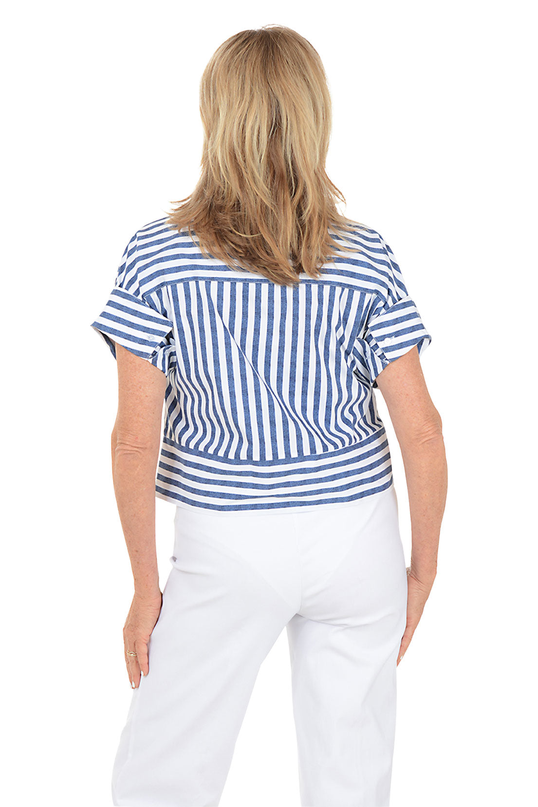 Woman wearing a blue and white striped shirt and white pants on a white background. Back shot.