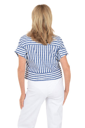 Woman wearing a blue and white striped shirt and white pants on a white background. Back shot.