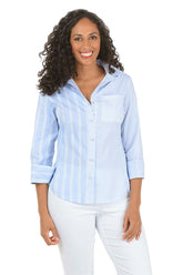Woman wearing a light blue striped shirt and white pants on a white background.