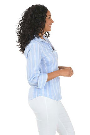 Woman wearing a light blue striped shirt and white pants on a white background. Side shot.