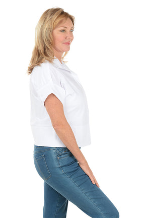 Woman wearing a white shirt and blue jeans on a white background. Side shot.