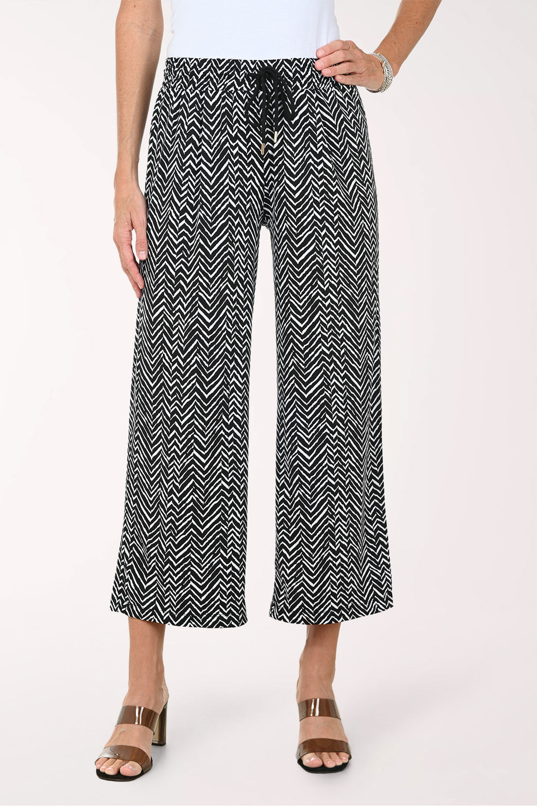 Person wearing black and white patterned wide-leg pants on a white background