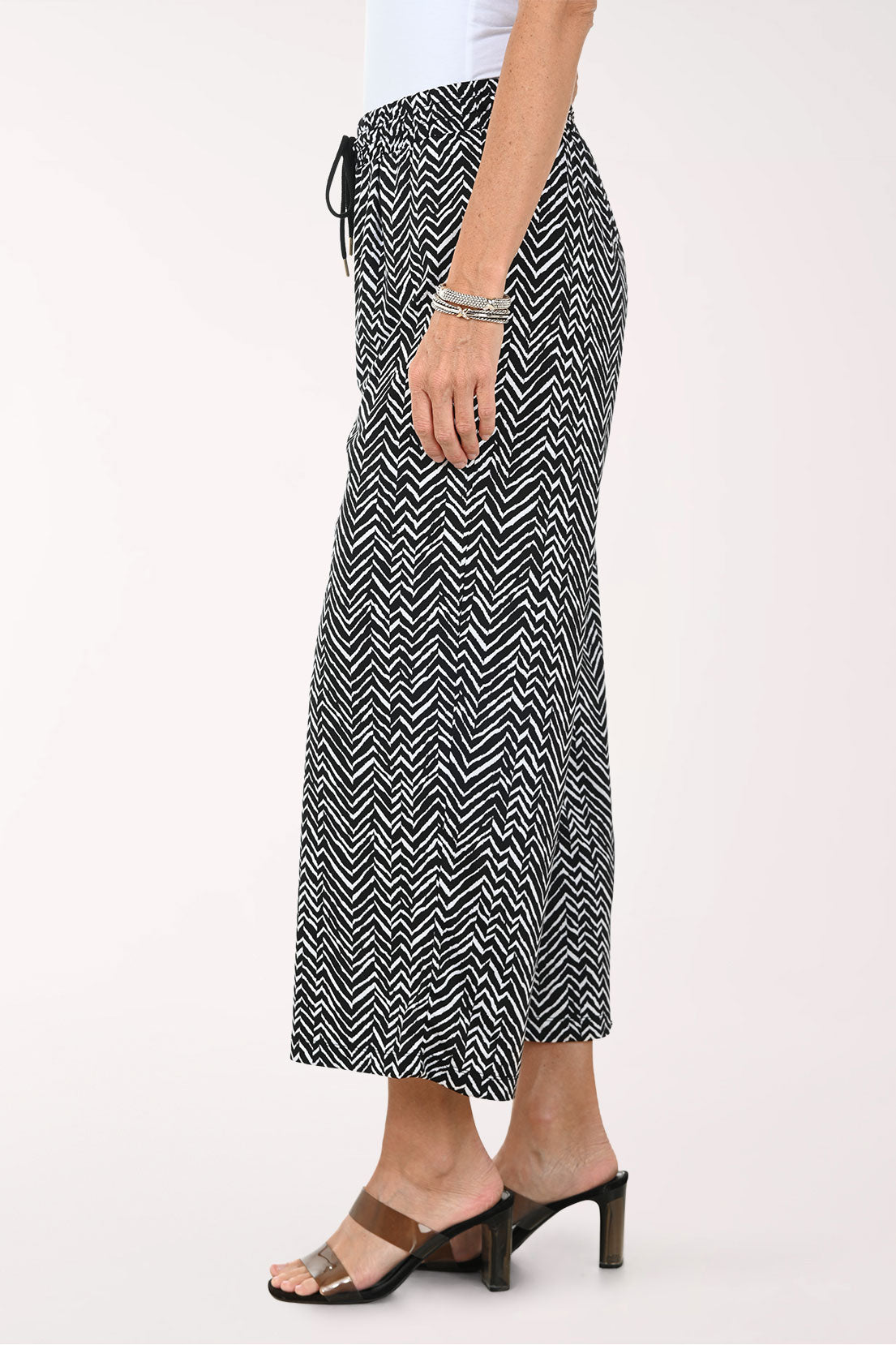 Person wearing black and white patterned wide-leg pants on a white background