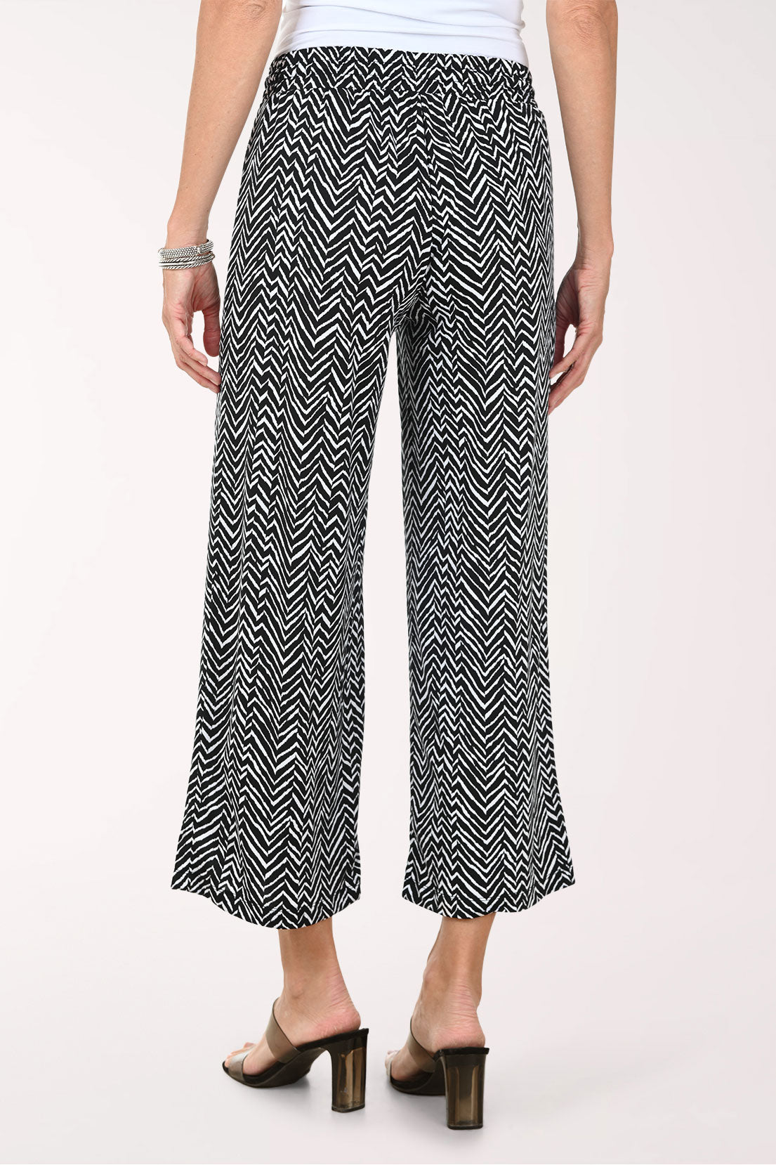 Person wearing black and white patterned wide-leg pants on a white background