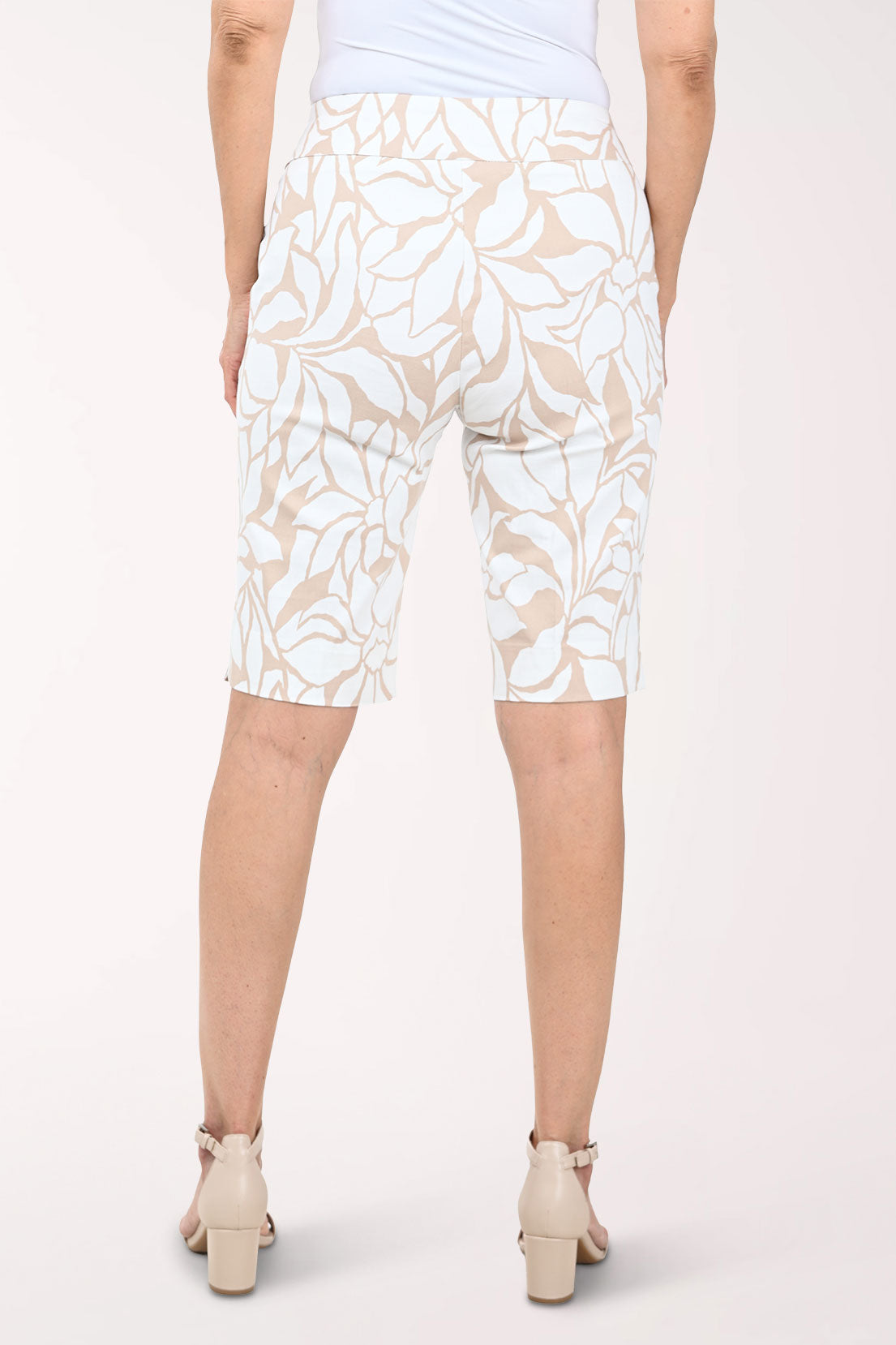 Person wearing white and beige floral patterned shorts on a white background