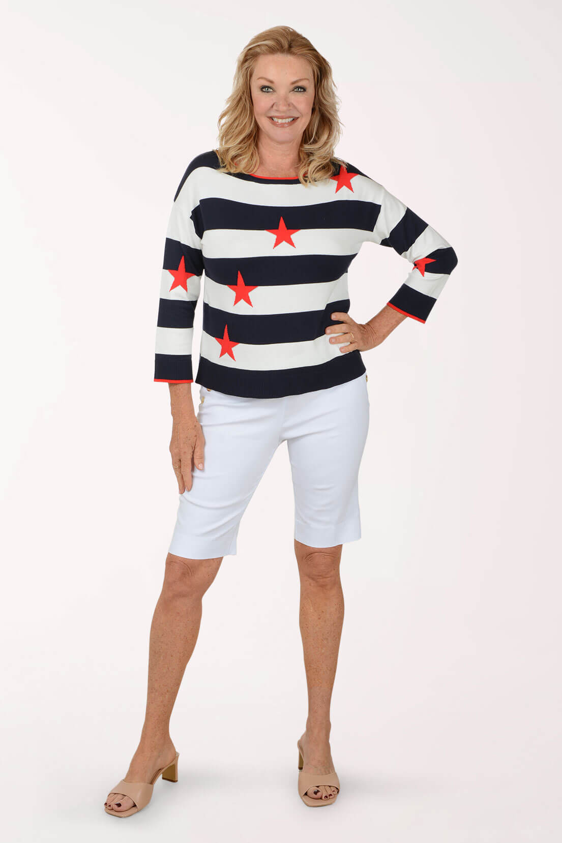 Woman wearing a striped sweater with red stars and white shorts on a white background