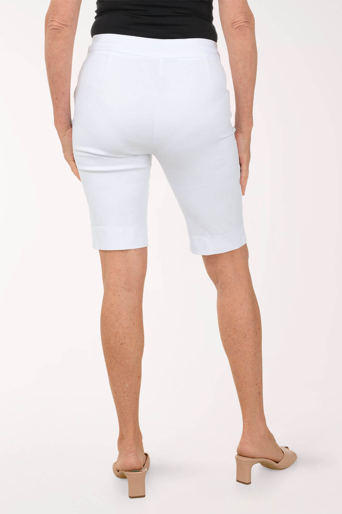 Person wearing white Bermuda shorts on a plain background