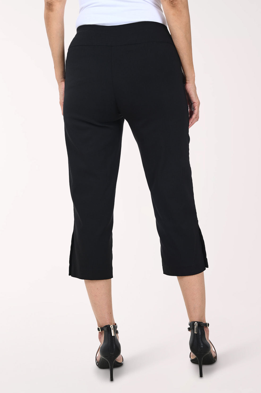 Person wearing black capri pants on a white background