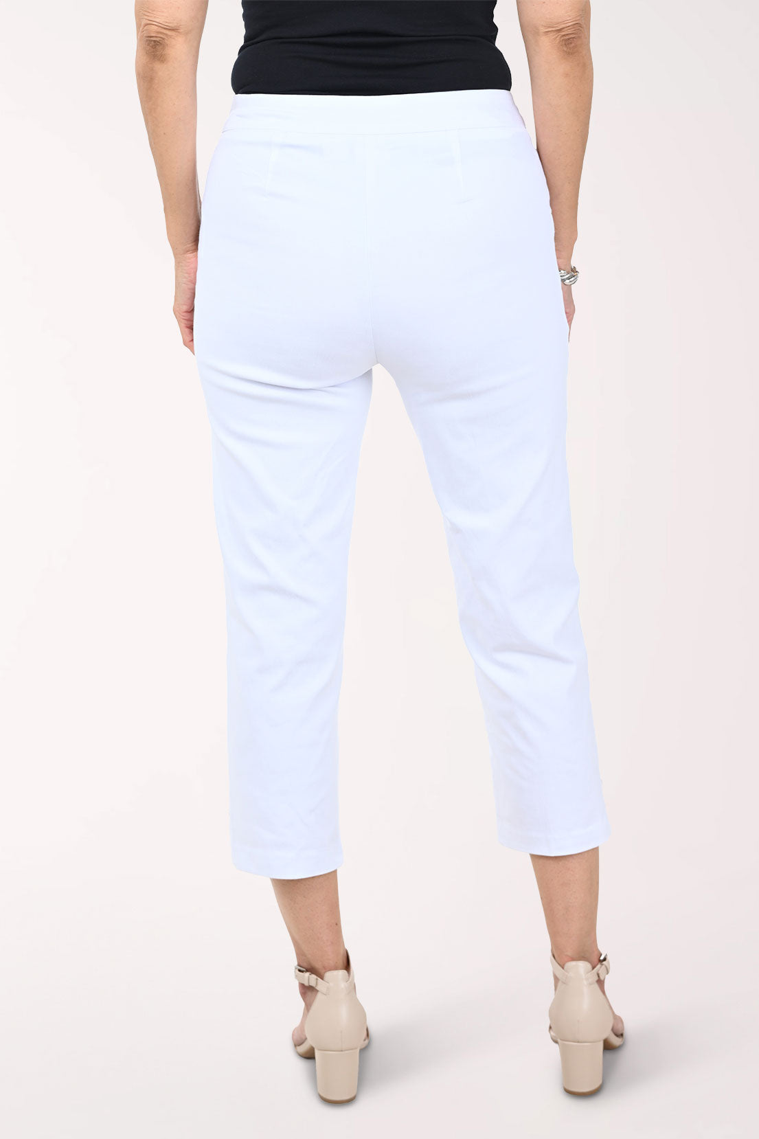 White capri pants worn by a person on a white background