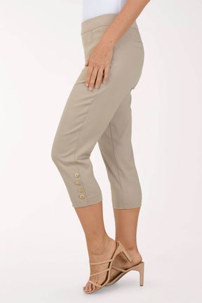 Beige capri pants with button details worn by a person on a white background