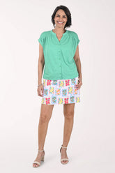 Woman wearing a green top and colorful skirt on a white background
