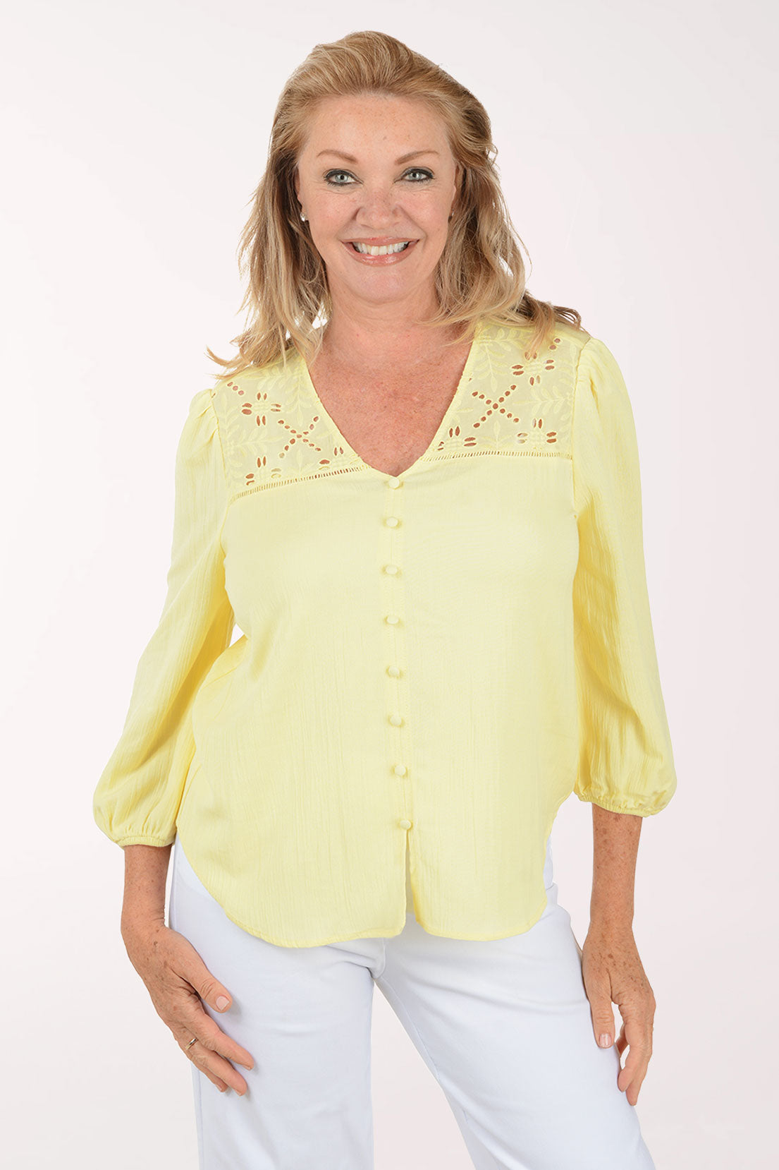 Woman wearing a yellow blouse with floral embroidery on a white background