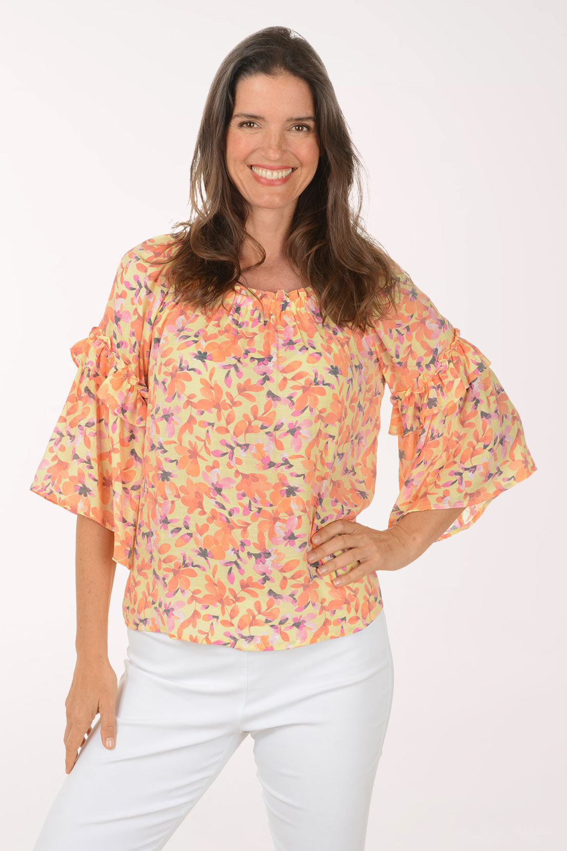 Woman wearing a colorful floral blouse with ruffled sleeves on a white background
