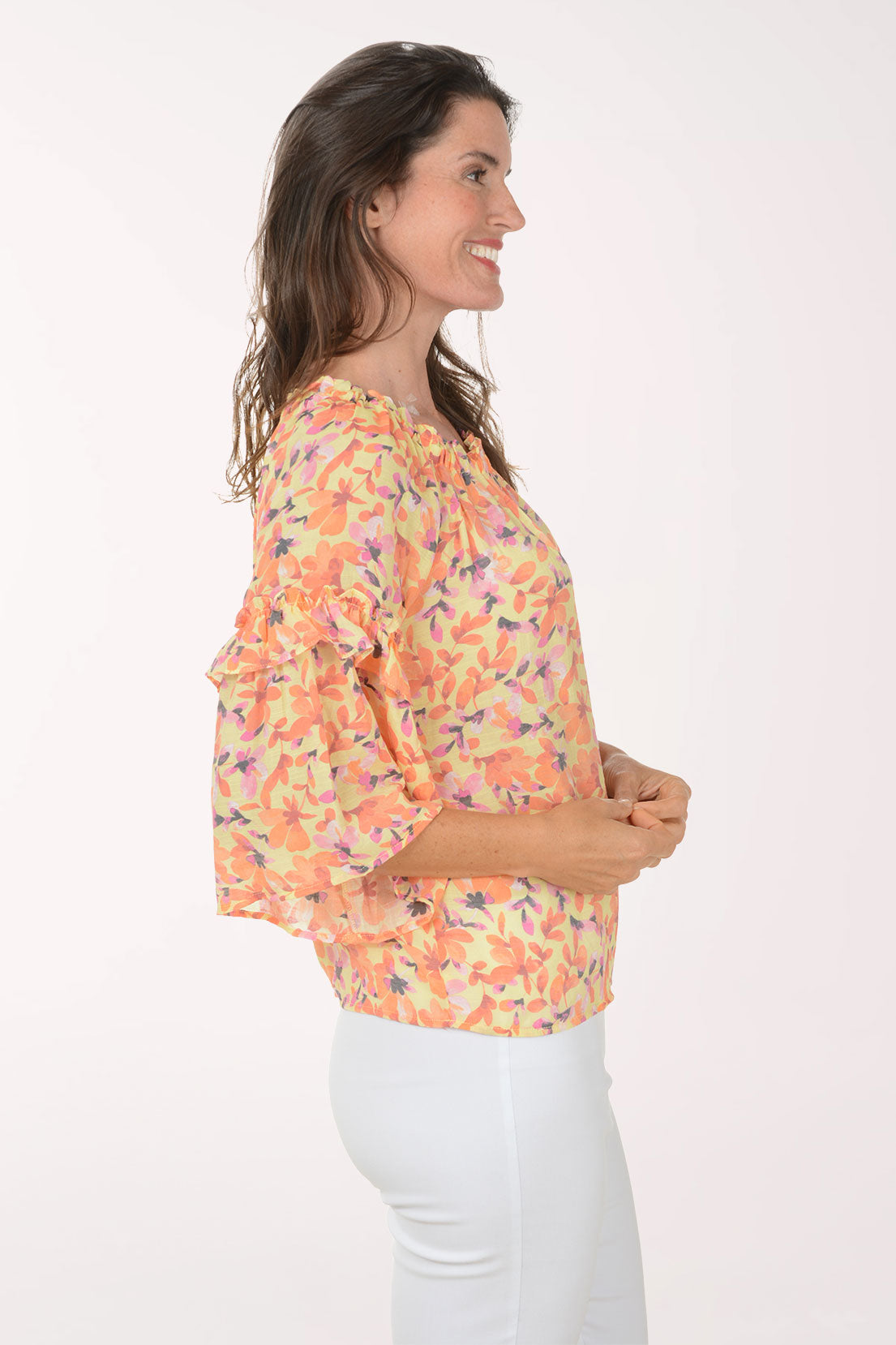 Woman wearing a colorful floral blouse with ruffled sleeves on a white background