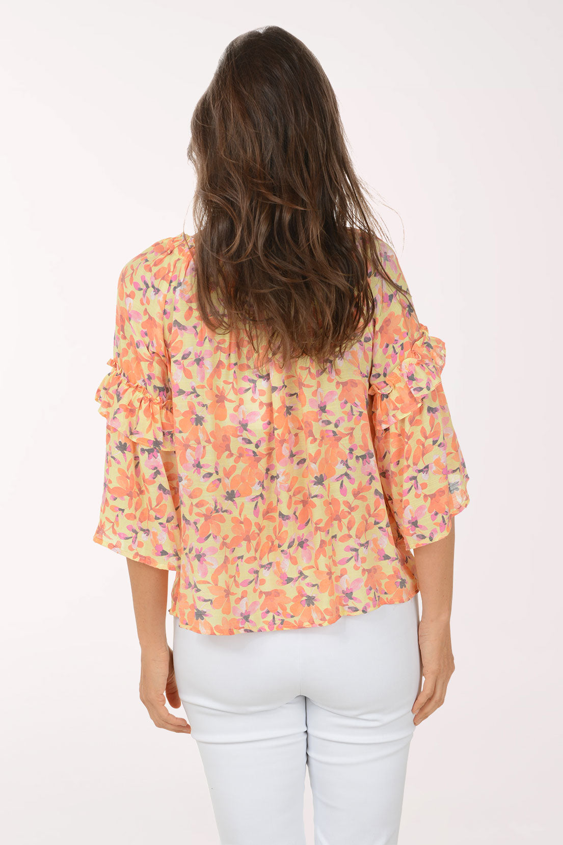Woman wearing a colorful floral blouse with ruffled sleeves on a white background