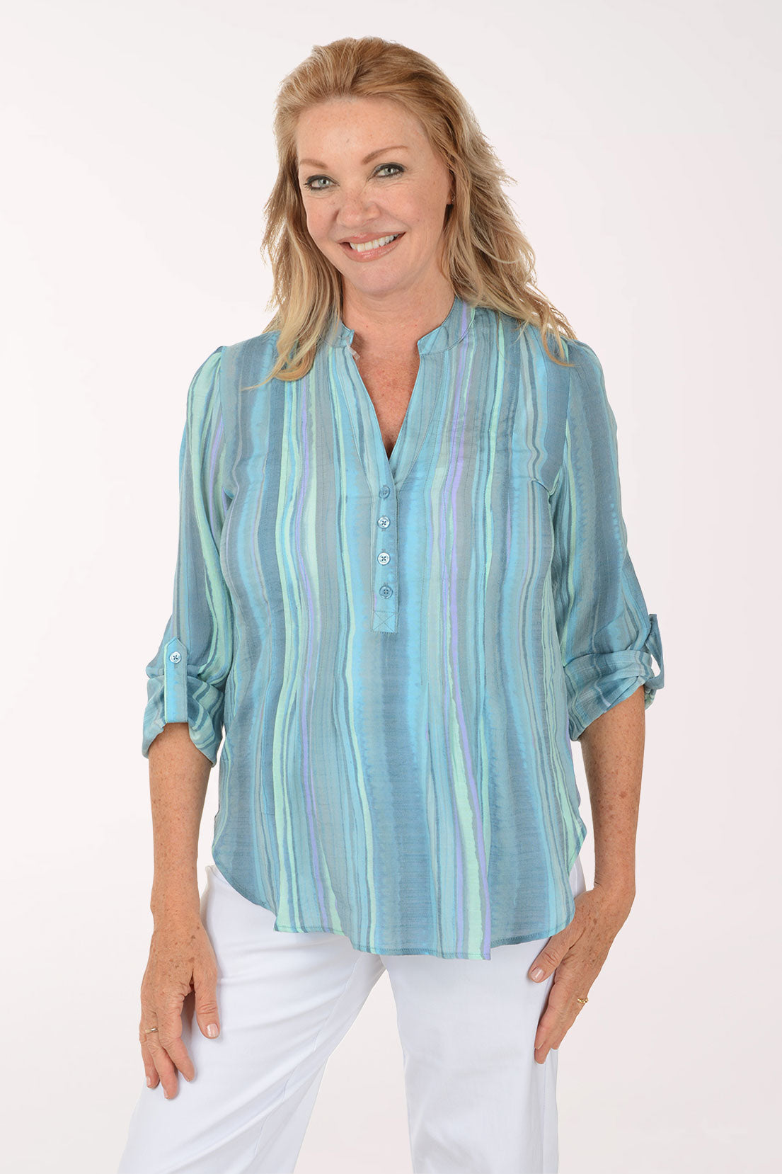 Woman wearing a light blue striped shirt and white pants on a white background