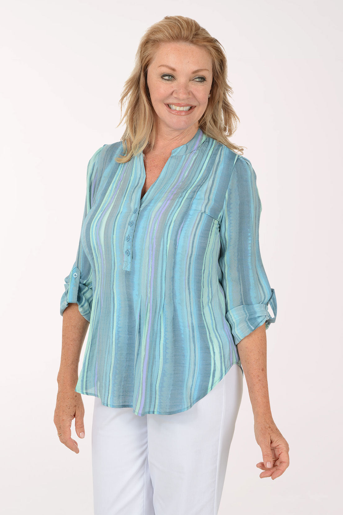 Woman wearing a light blue striped shirt and white pants on a white background