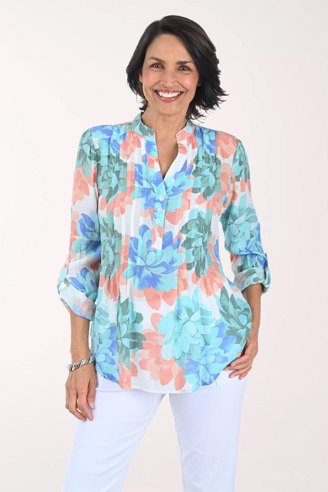 Woman wearing a colorful floral blouse against a white background