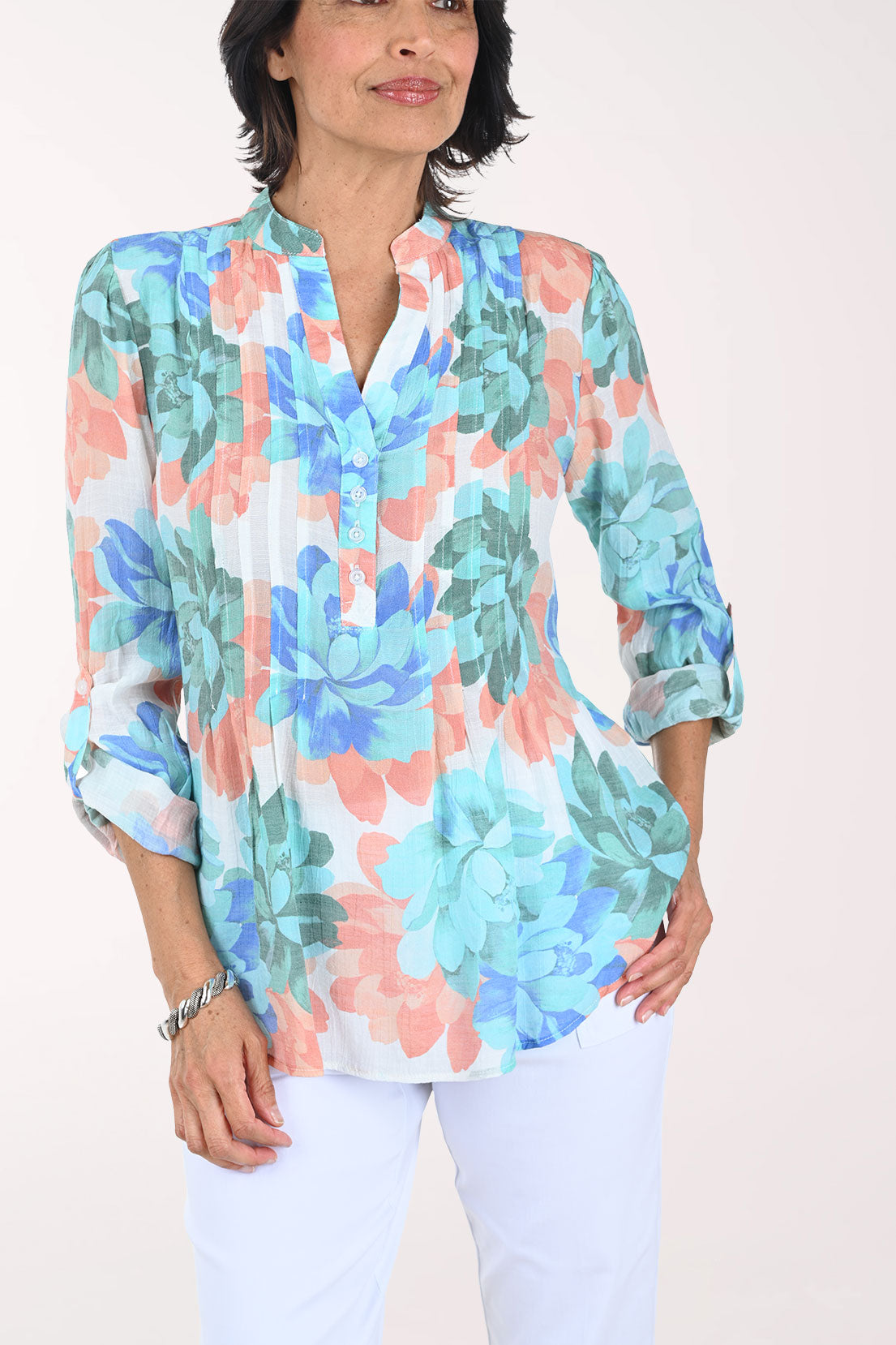 Woman wearing a colorful floral blouse against a white background