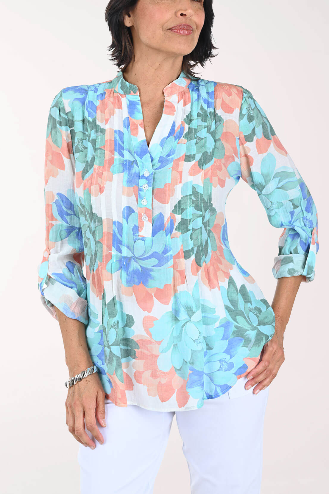 Close front view of the blouse showing the split V-neck, mandarin collar, buttoned half placket, and fine pleats down the front in the turquoise, blue, coral, and sage floral print.