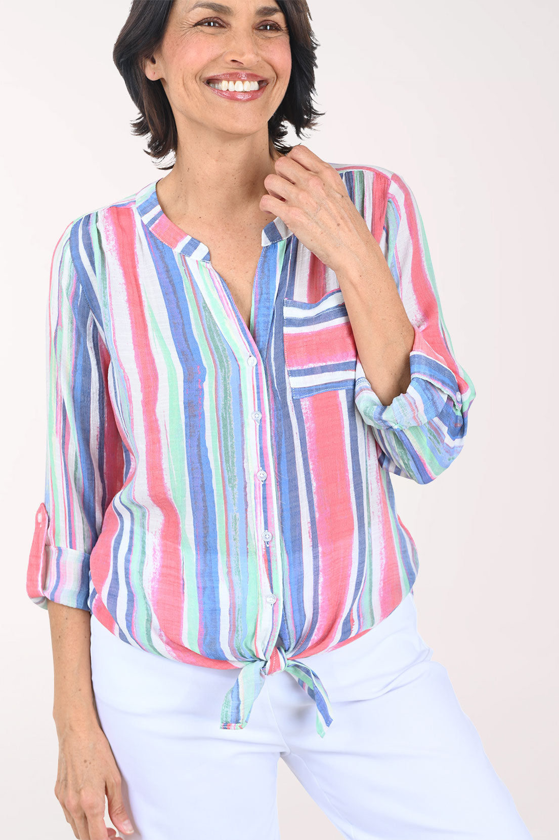 Woman wearing a colorful striped shirt and light pants on a white background