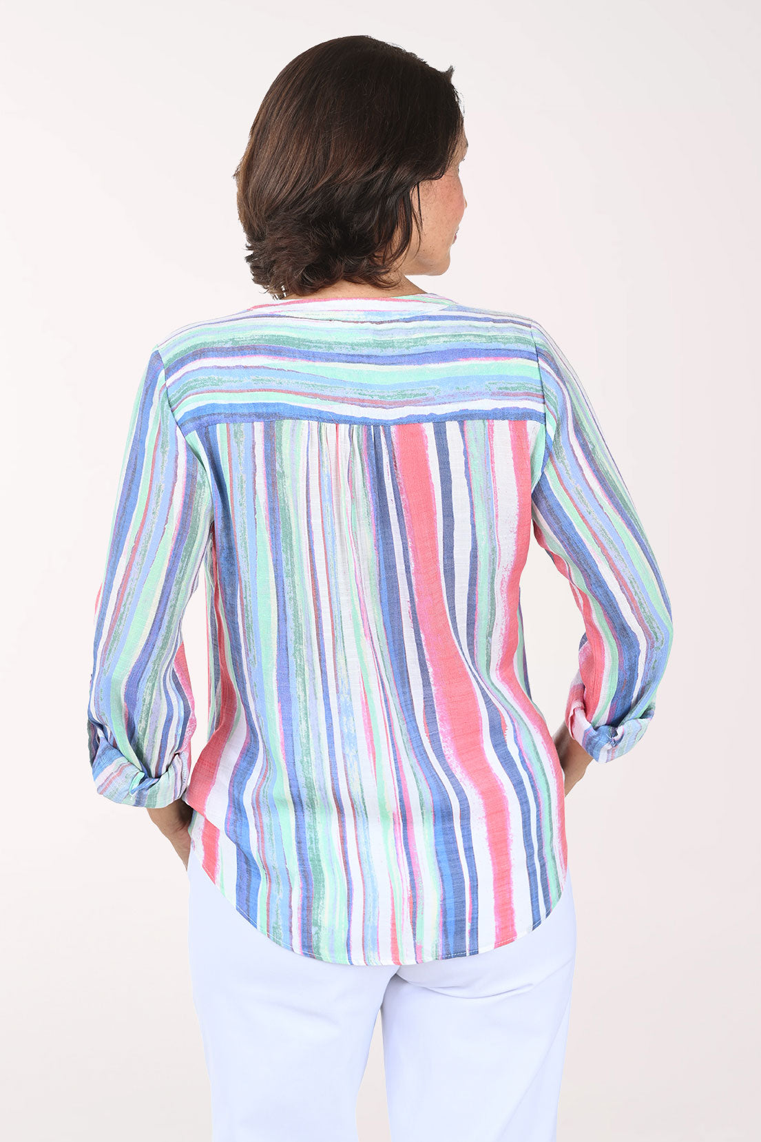 Woman wearing a colorful striped shirt and light pants on a white background