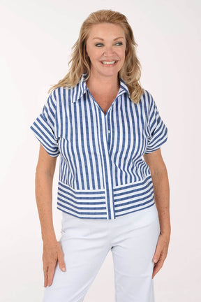 Woman wearing a blue and white striped shirt and white pants on a white background