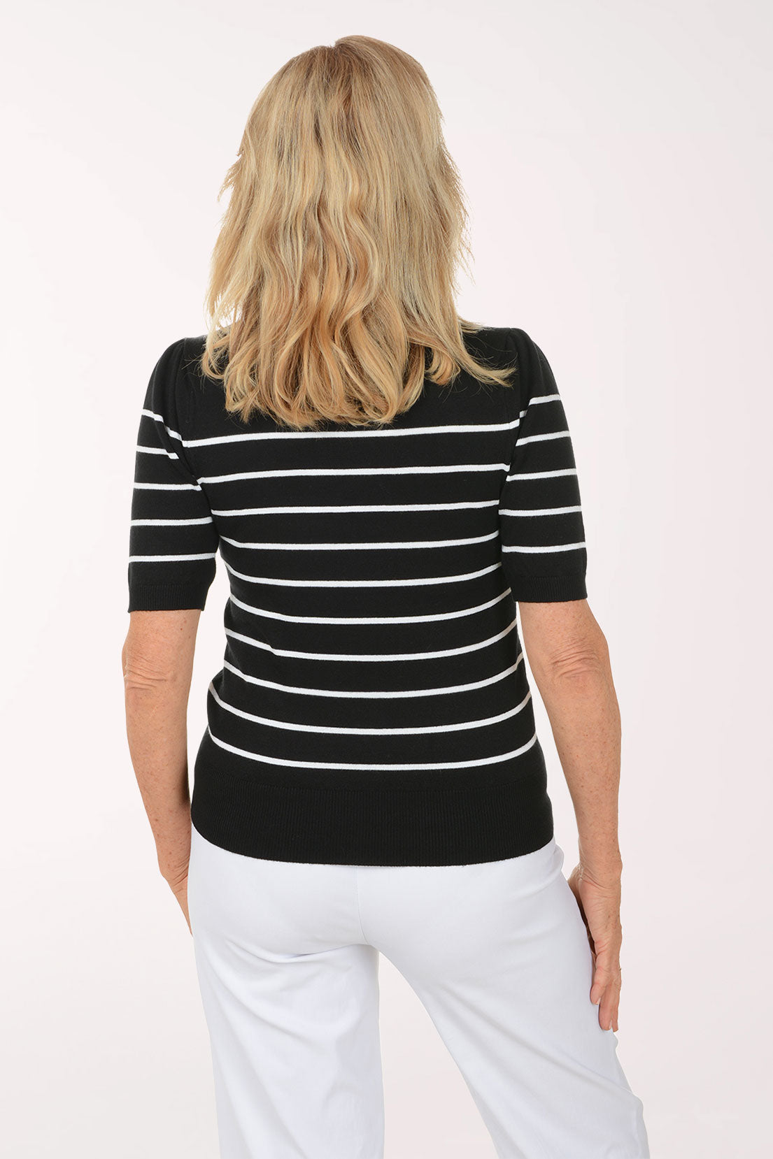 Woman wearing a black and white striped shirt with butterfly designs on a white background