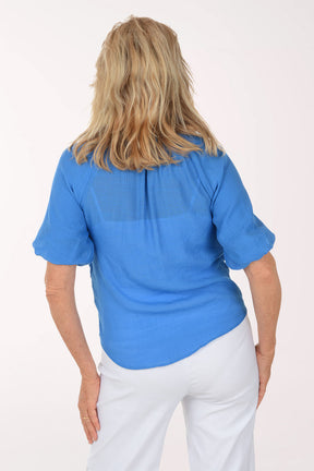 Woman wearing a blue blouse and white pants on a white background