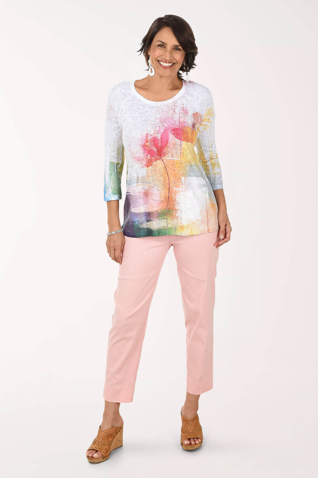Woman wearing a colorful top and pink pants on a white background