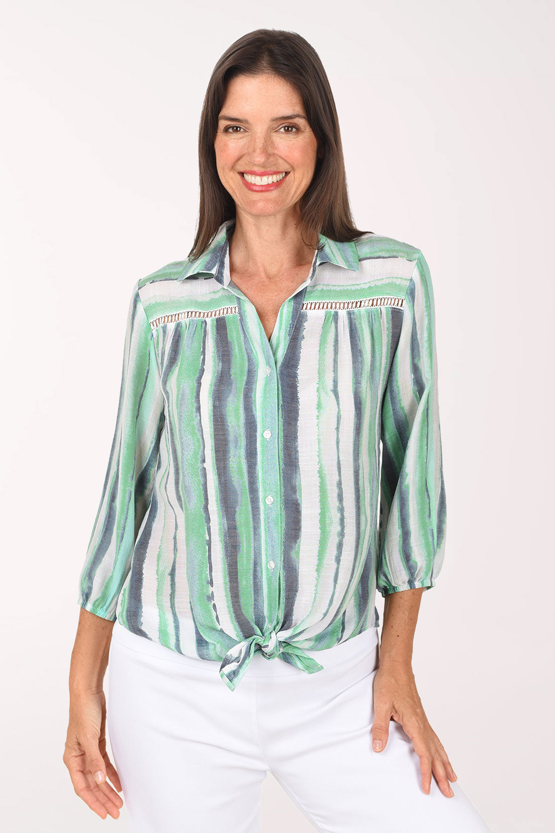 Model wearing the Zac and Rachel Green Gulfstream Striped Crochet Detail Shirt, watercolor stripes in green, mint, navy and white, tied at the front over white pants