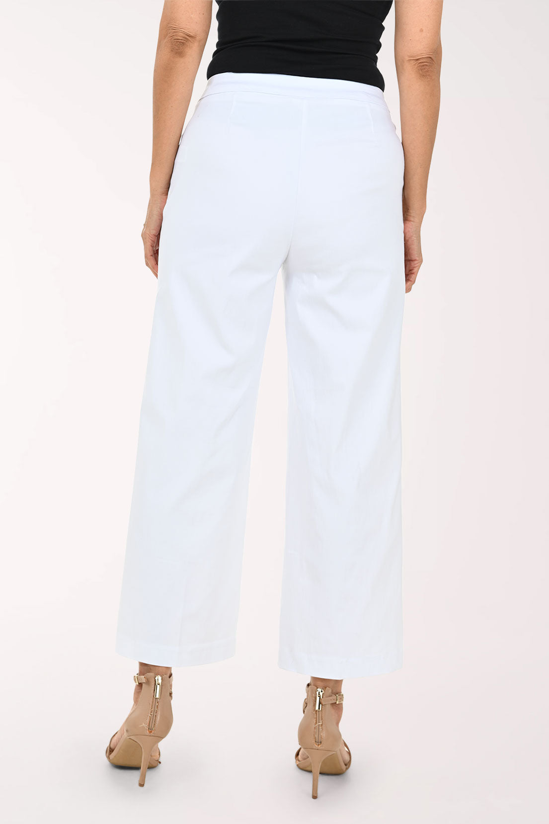 White cropped wide-leg pants with decorative gold-tone buttons on the sides, shown on a model wearing a black top and beige strappy heels against a light studio background.