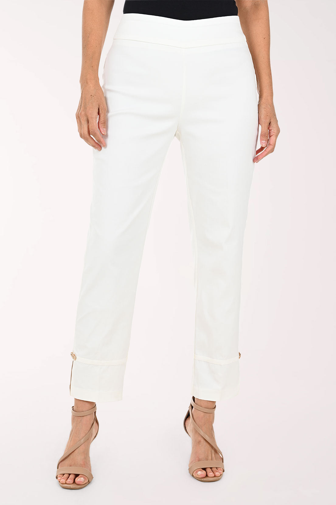 White cropped ankle pants with rolled cuffs and small side zippers, shown on a model wearing beige strappy heels against a plain light background.