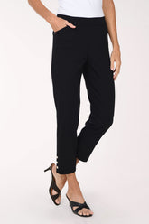 A person modeling black cropped pants with three decorative gold-tone buttons at the hem, paired with black mule sandals against a plain light background.