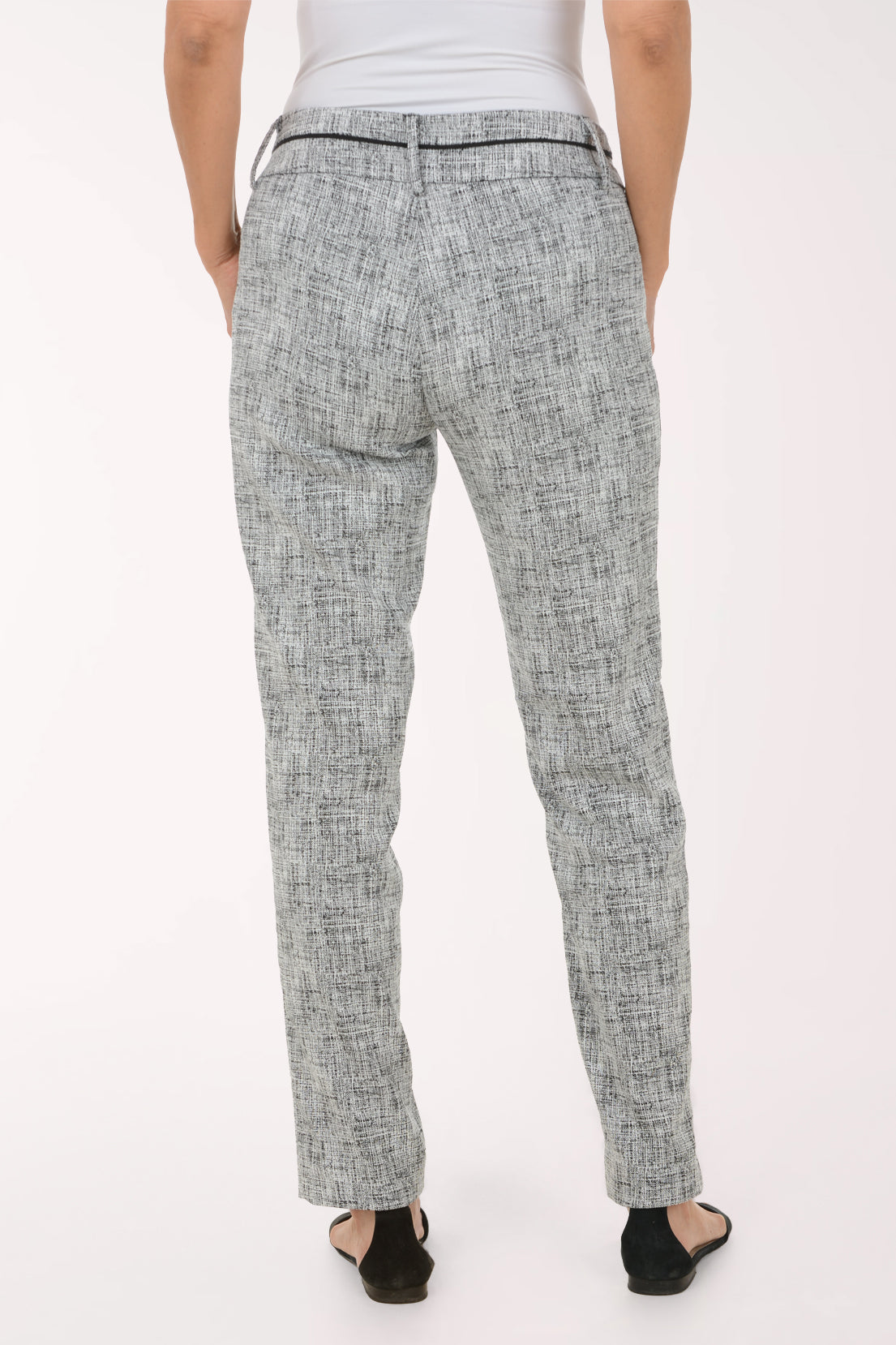 A model wearing a pair of slim-fit trousers in a gray and white textured tweed pattern, paired with black slide sandals against a plain white studio background.