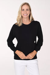 Woman wearing a sold black sweater with a pearl button accent on waist