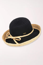 Black straw hat with a natural ribbon on a light pink background